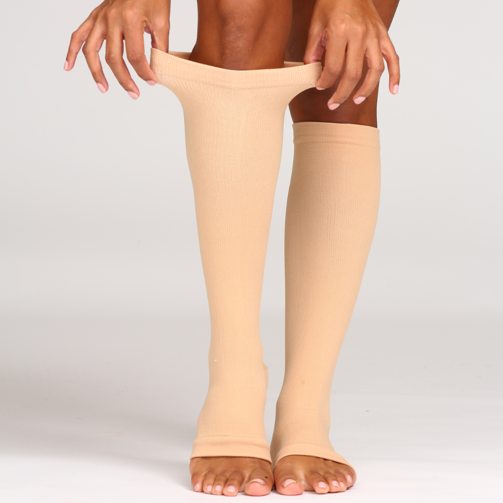Pulling up a beige open toe knee high compression sock