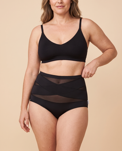 Woman wearing black high waisted tummy control knickers with cross band mesh panels